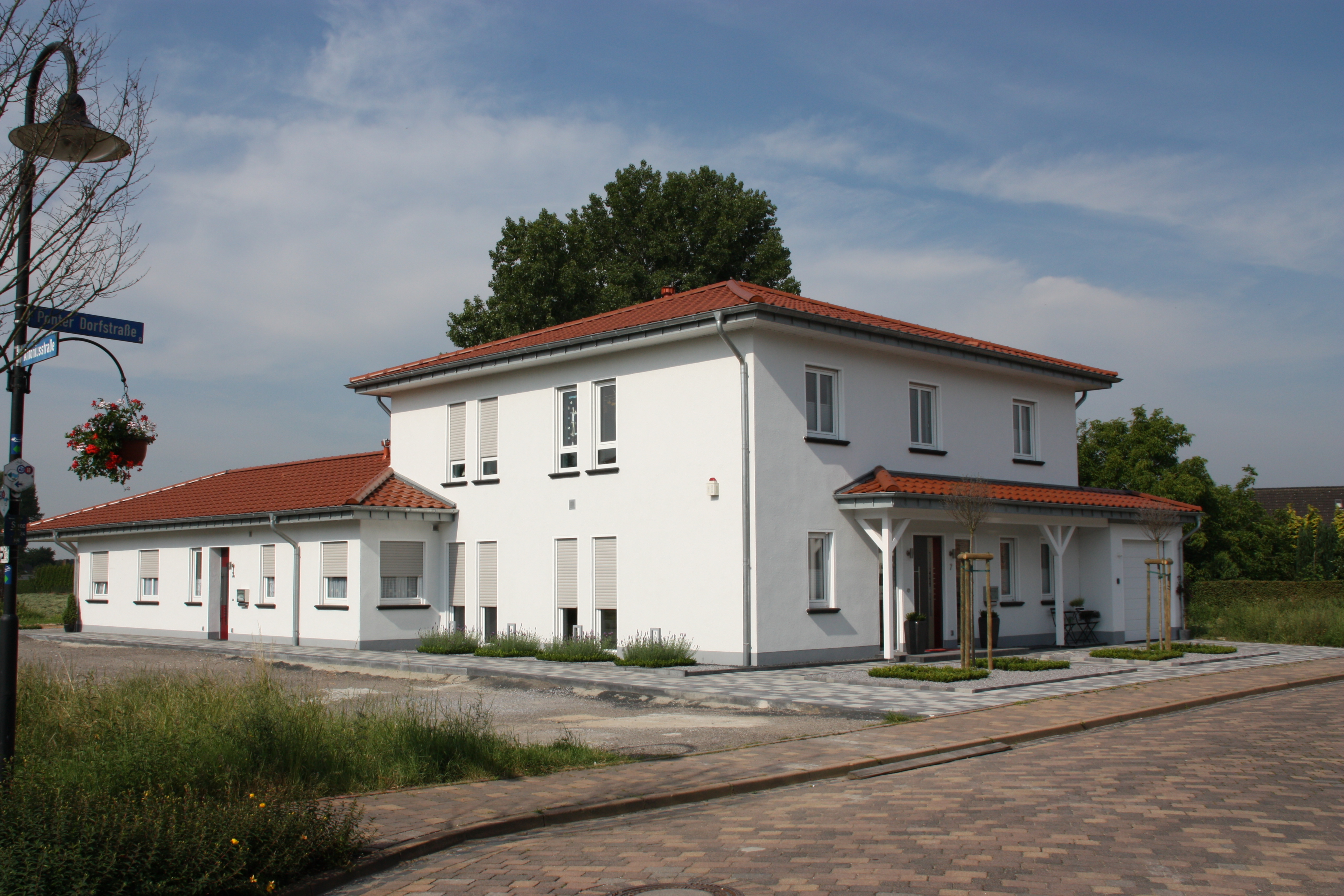 Ländliches Wohnhaus mit neuen Fenstern in weiß. Das Haus ist im Panorama zu sehen und hat weiße Wände sowie ein Dach mit roten Dachpfannen